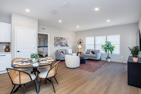 A dining table with chairs is in the middle of a living room.