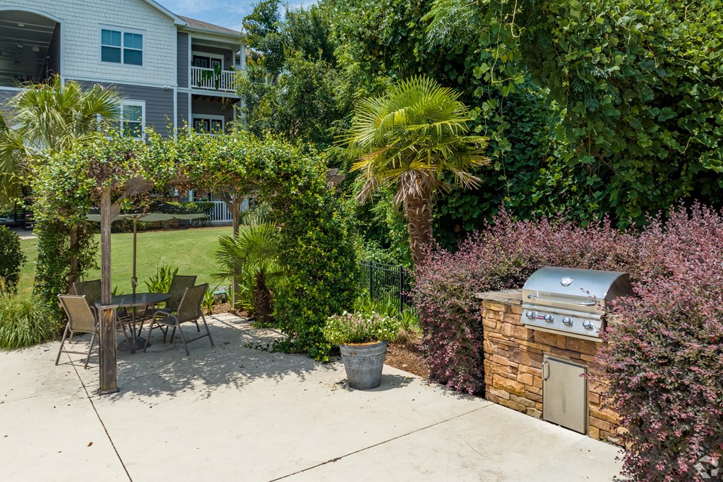 a patio with a grill and a table and chairs