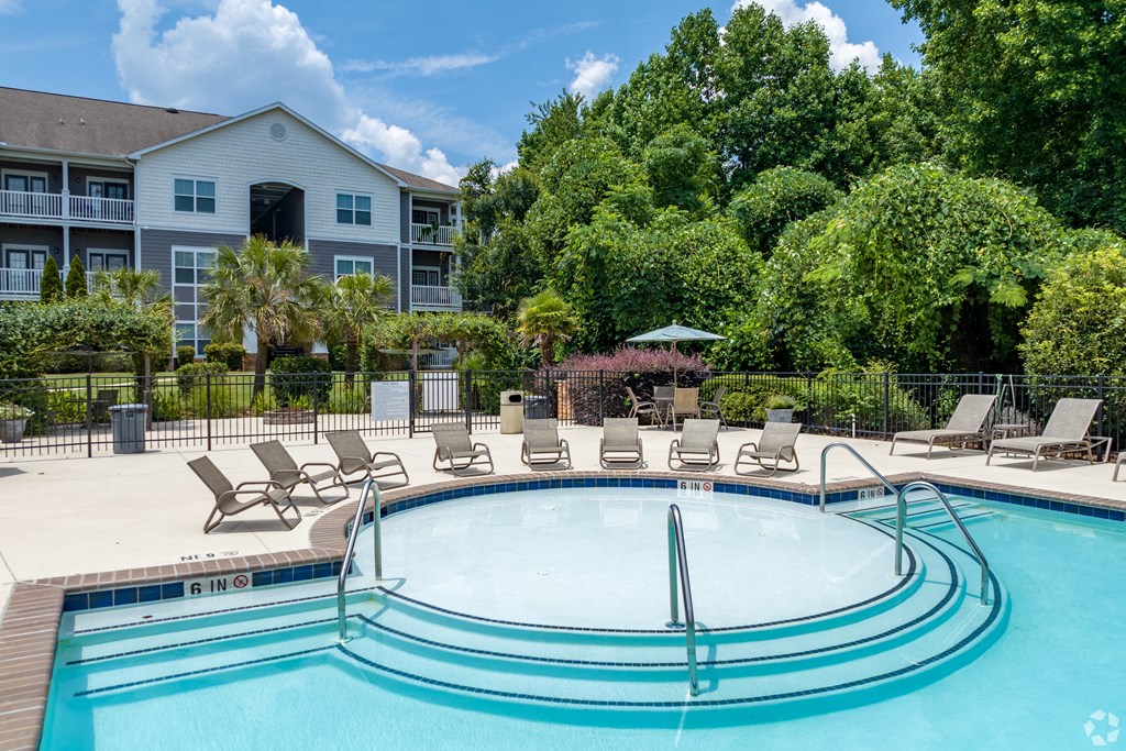 a pool with lounge chairs and umbrellas in front of a building