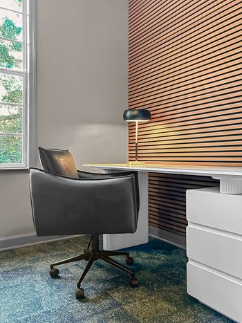 A black chair is in front of a window with blinds.