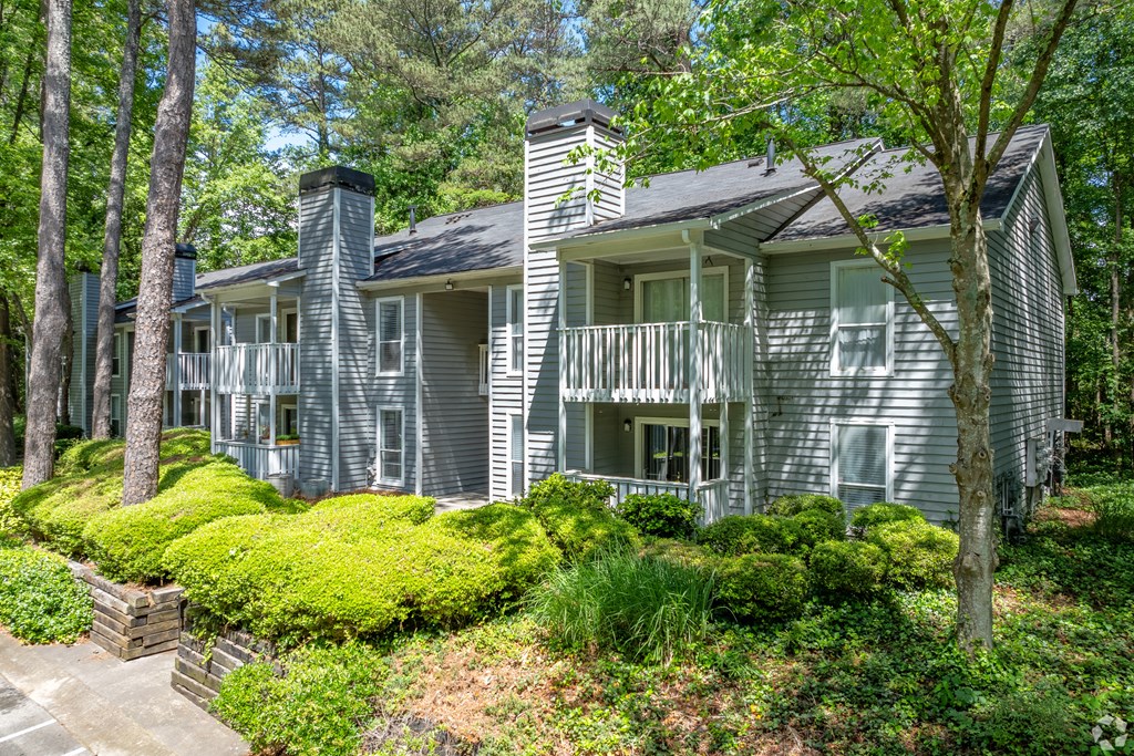 the view of a gray house with a deck and trees