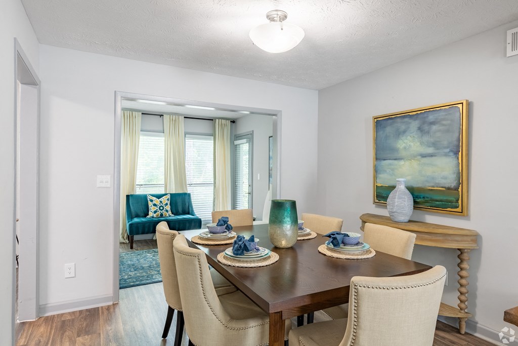a dining room with a table and chairs and a living room with windows