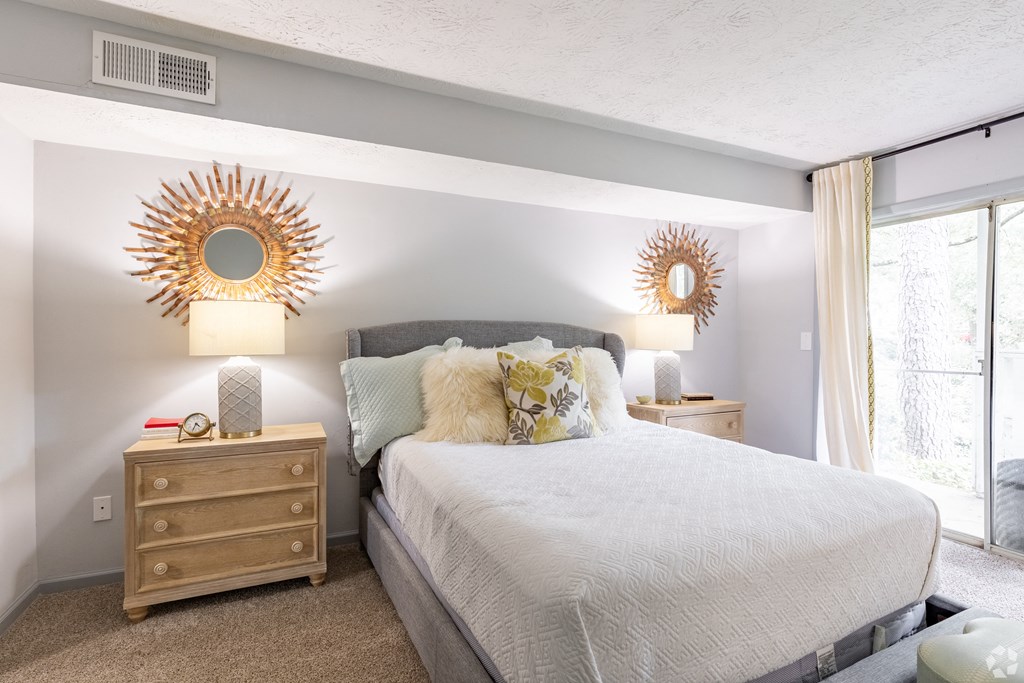 a bedroom with a bed and two mirrors on the wall