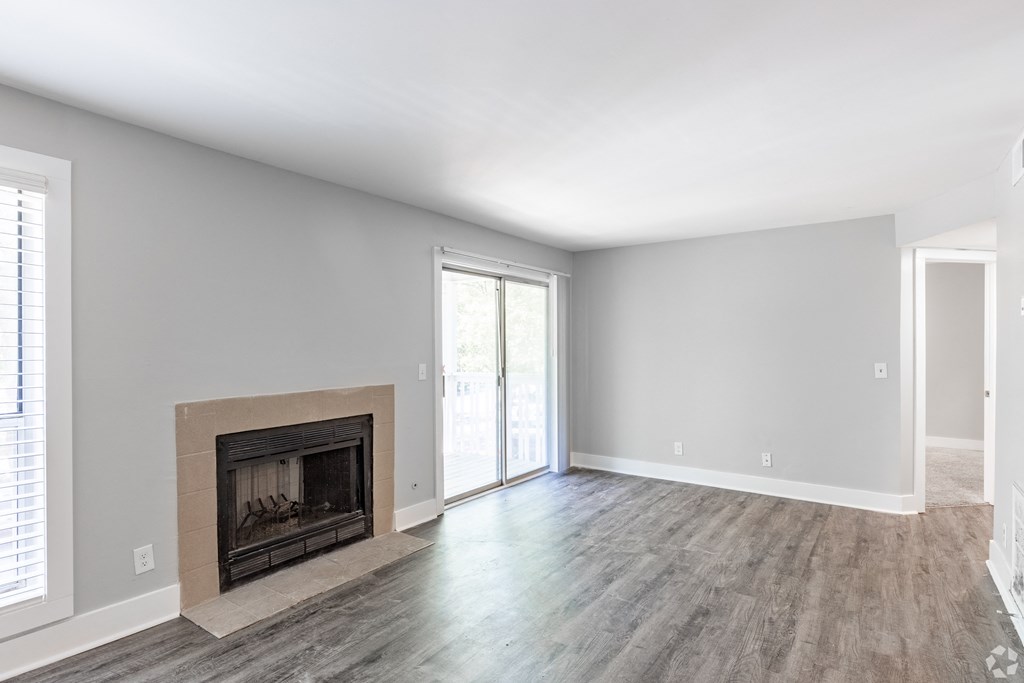 an empty living room with a fireplace and a sliding glass door