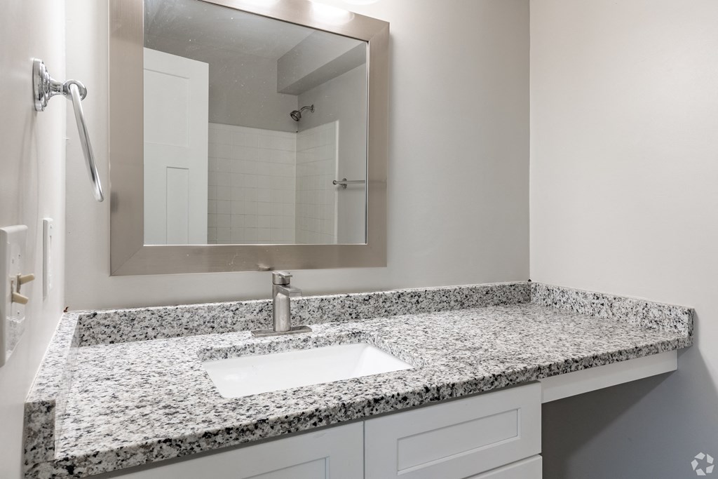 a bathroom with granite counter top and a sink and a mirror