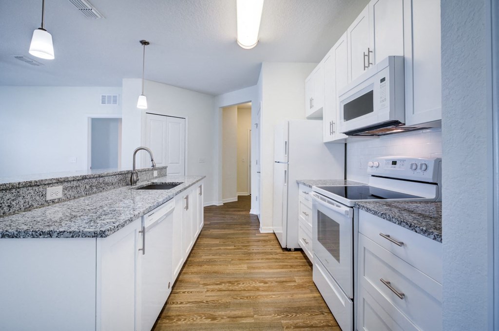 a kitchen with white cabinetry and granite countertops  at Century Avenues, Lakeland, 33813
