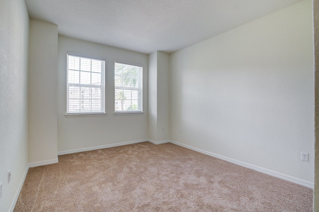 a bedroom with two windows and a carpeted floor  at Century Avenues, Lakeland, FL