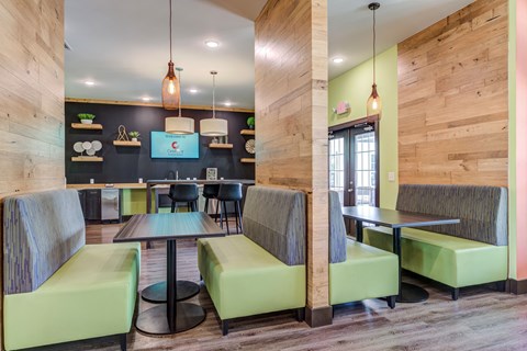 a common area with tables and chairs and a kitchenette in the background