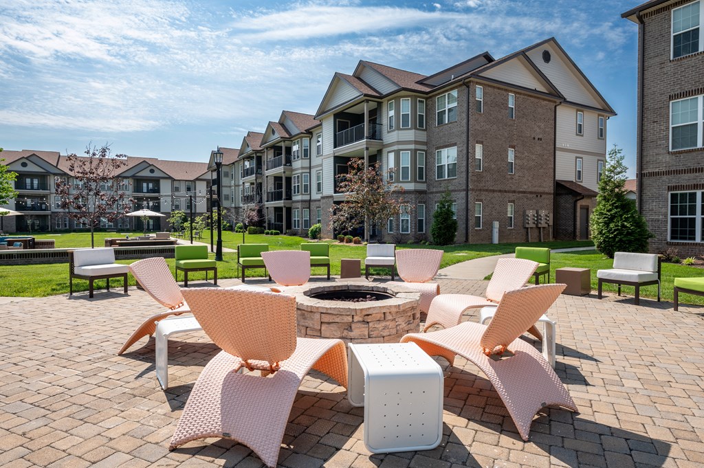 an outdoor lounge area with chairs and a fire pit at the enclave at woodbridge apartments in at Century Belmont Station, Louisville, KY