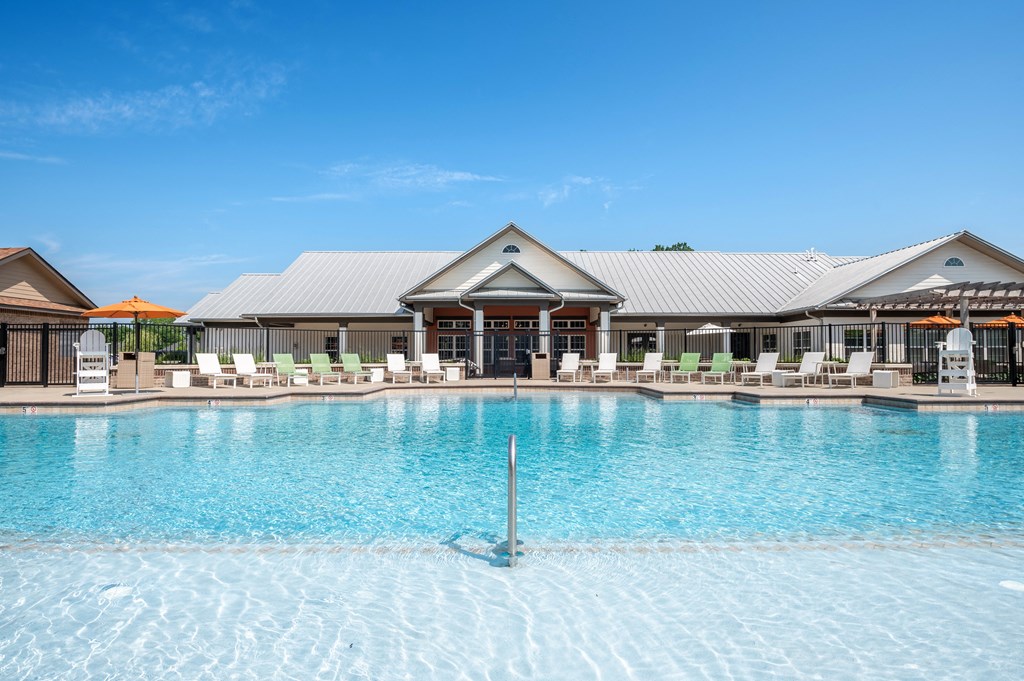 a large pool with lounge chairs and umbrellas in front of a building at Century Belmont Station, Louisville