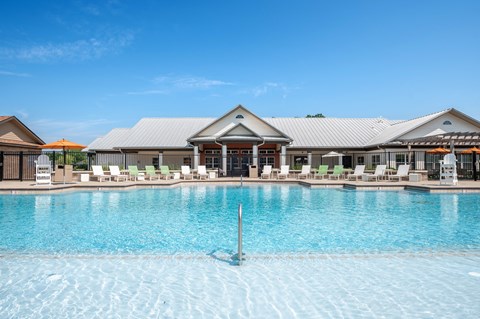 a large pool with lounge chairs and umbrellas in front of a building at Century Belmont Station, Louisville