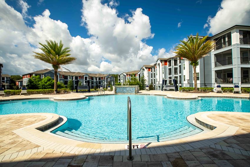 a large swimming pool with apartments in the background