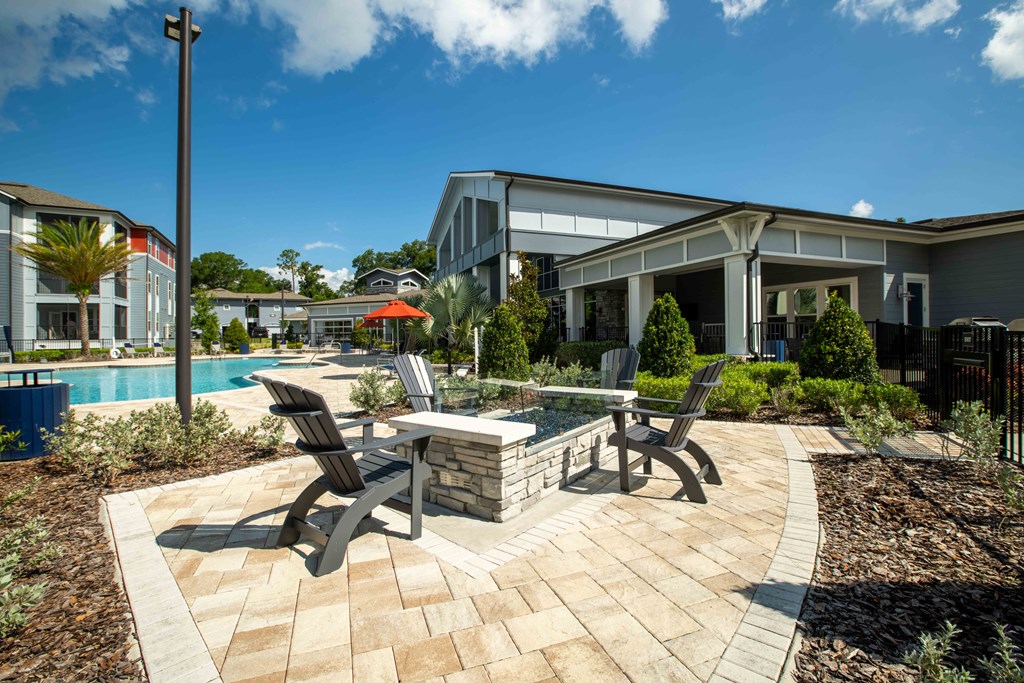 a patio with chairs and a table next to a swimming pool at Century Dunes Apartments, Deland, FL, 32724