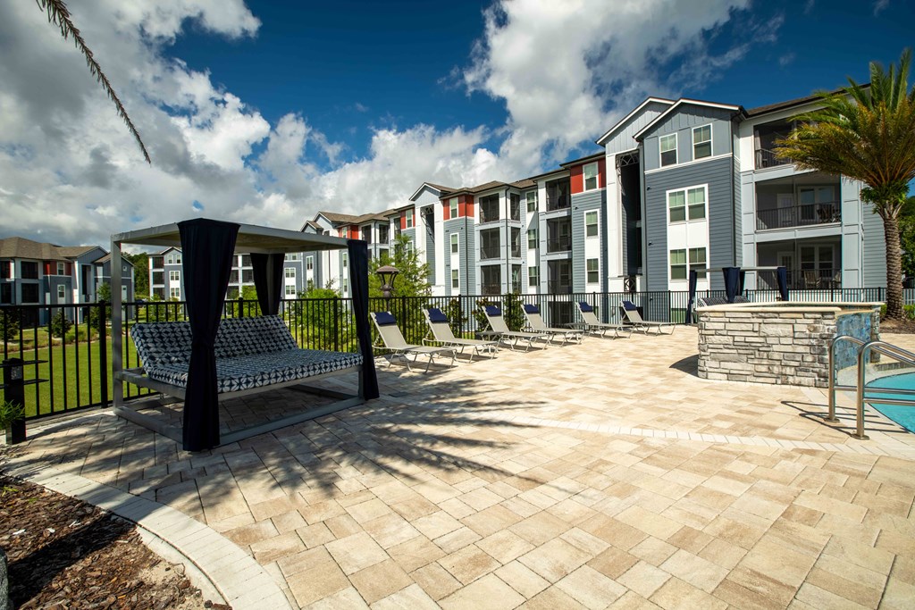 a courtyard with benches and a pool in front of an apartment building at Century Dunes Apartments, Deland, FL, 32724