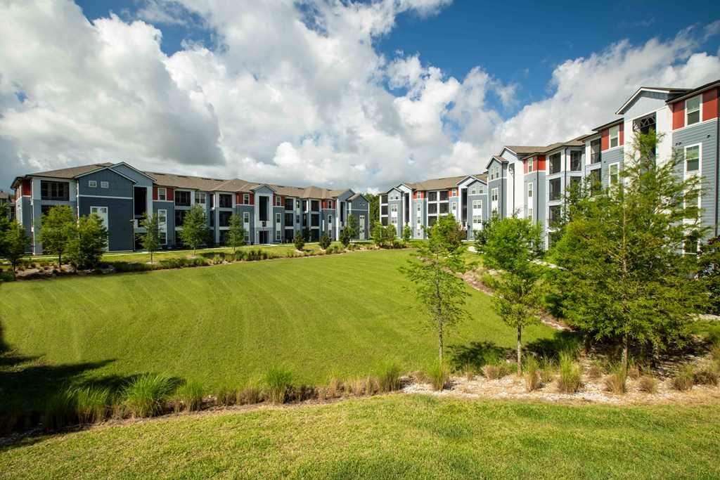 an exterior view of an open field in front of an apartment building at Century Dunes Apartments, Deland, 32724