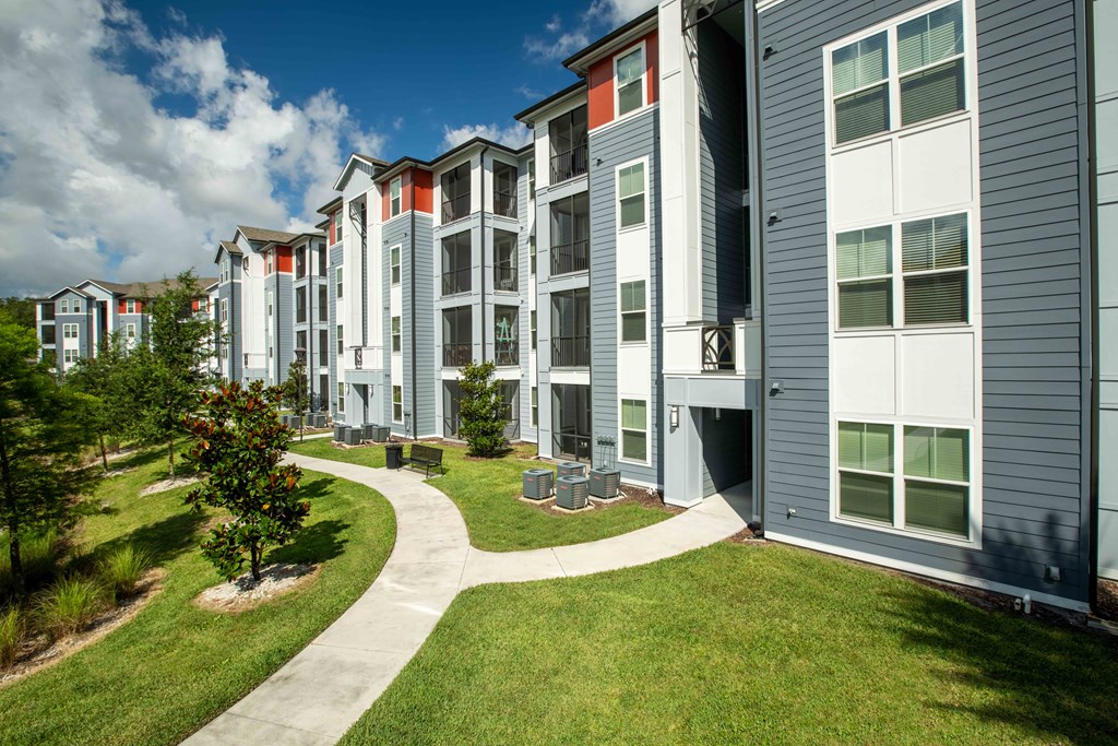an exterior view of an apartment building with grass and trees at Century Dunes Apartments, Florida