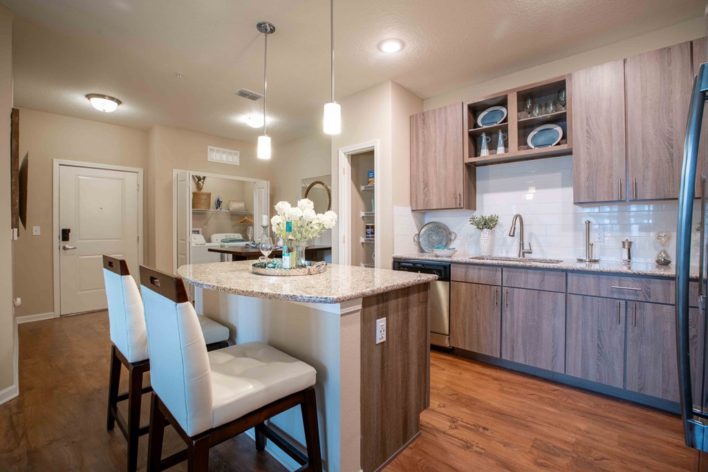 a kitchen with a bar and white chairs at Century Dunes Apartments, Deland, Florida