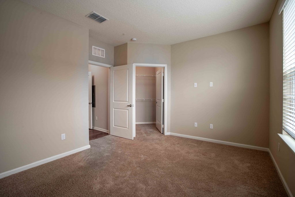 a living room with carpet and a door to a closet at Century Dunes Apartments, Deland, FL