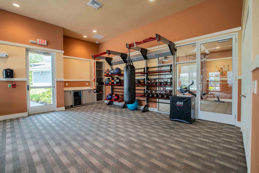 a gym with a punching bag and weights in the corner of a room at Century Dunes Apartments, Deland, 32724