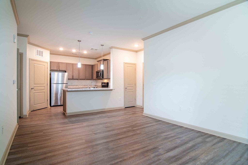 a living room and kitchen with white walls and wood floors  at Century New Holland, Gainesville