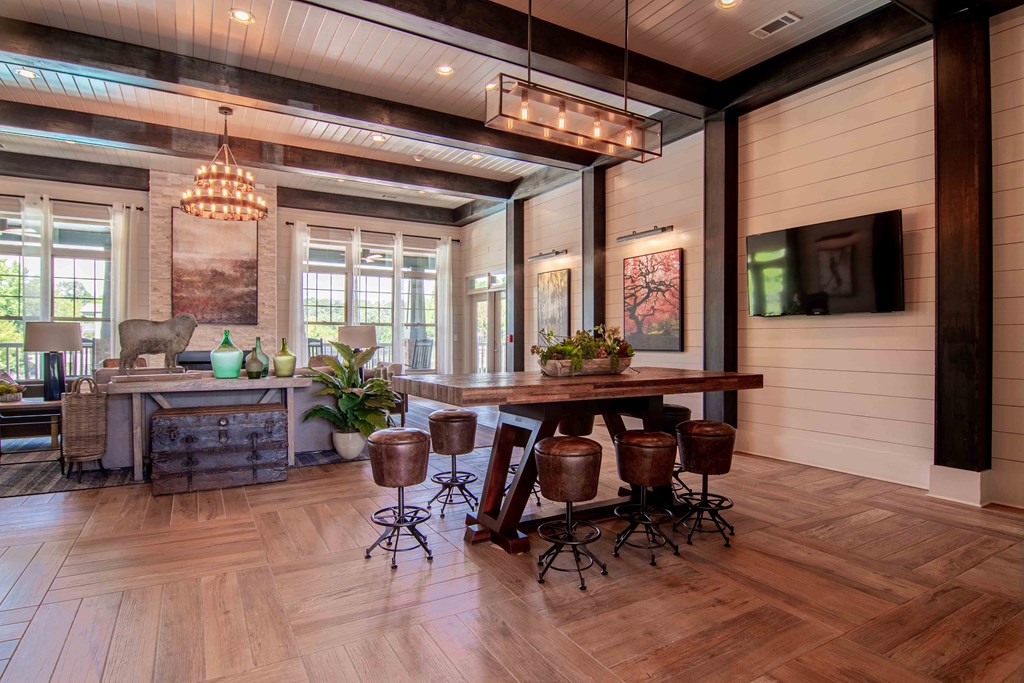 a large living room with a wooden floor and a table with stools at Century New Holland, Gainesville, GA