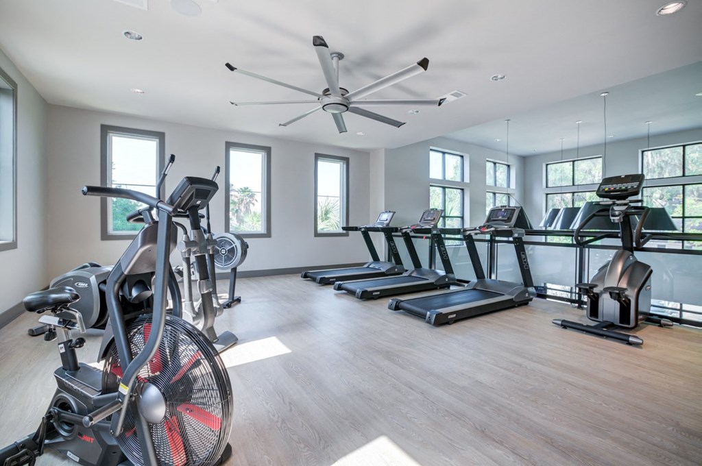 a gym with treadmills and weights and a ceiling fan at Century Town Center, Gainesville