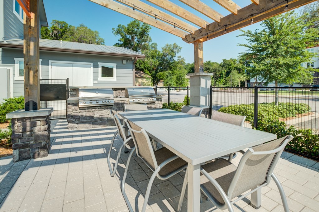 a dining area with a table and chairs under a pergola at Century Town Center, Gainesville, FL