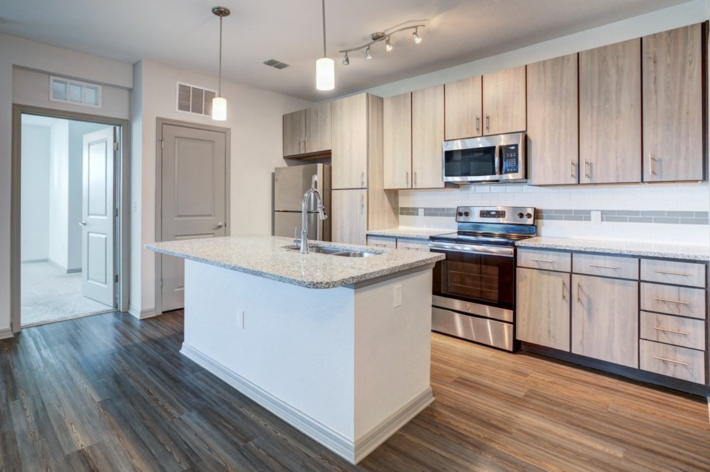 a kitchen with a large island and wooden floors and cabinets at Century Town Center, Gainesville