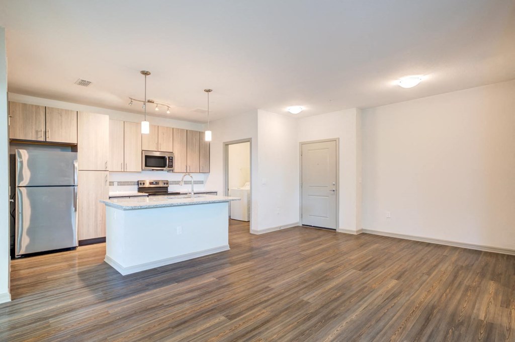 an empty living room with a kitchen with stainless steel appliances at Century Town Center, Florida