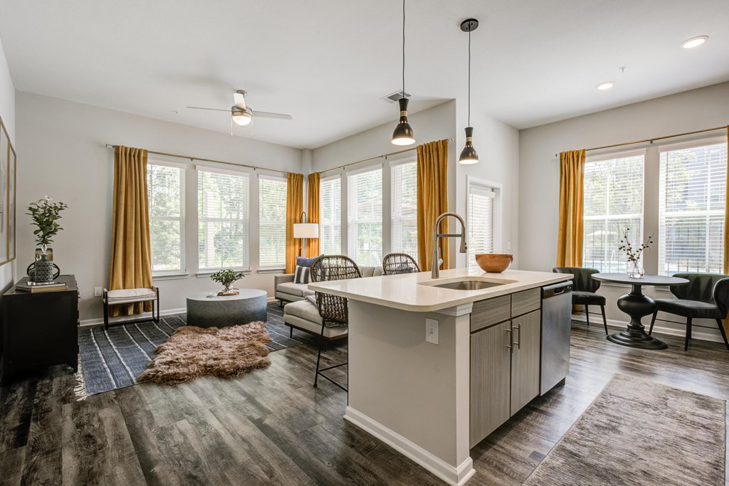 an open floor plan with a kitchen island and a living room with a couch and chairs at Century University City, North Carolina