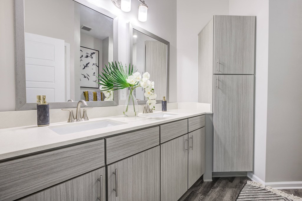 a bathroom with gray cabinets and white countertops at Century University City, Charlotte, North Carolina