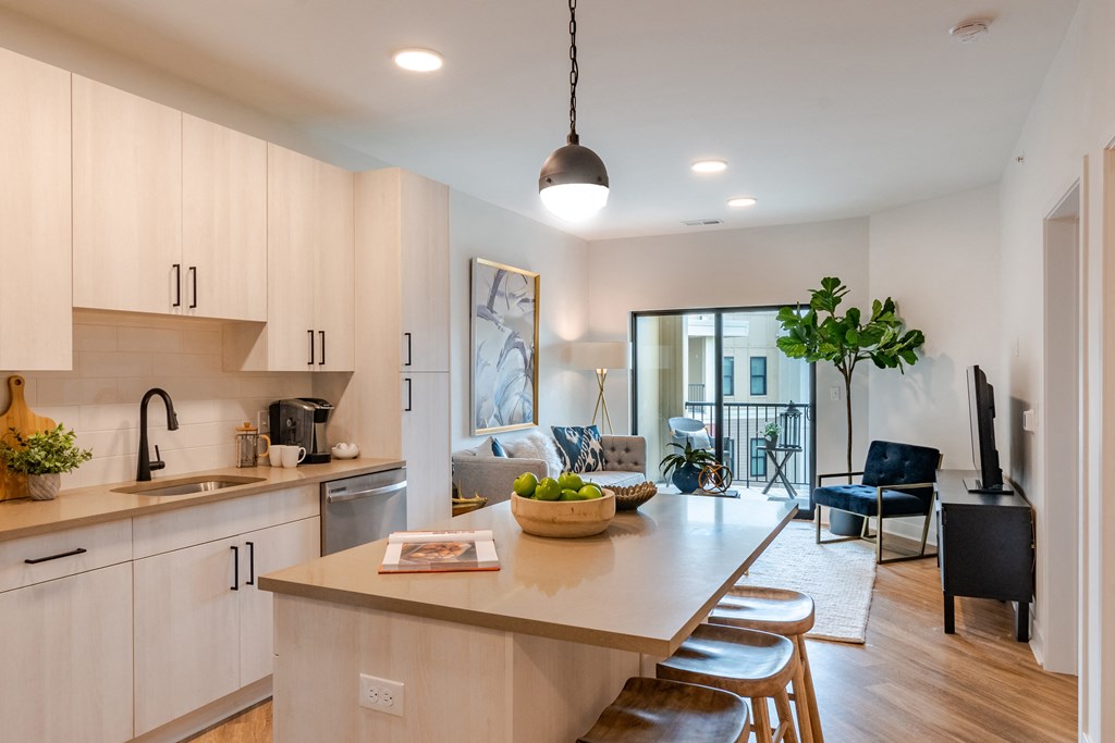 a kitchen with white cabinets and a large island with a bowl of fruit on it  at Century West Pryor, Lee's Summit, MO