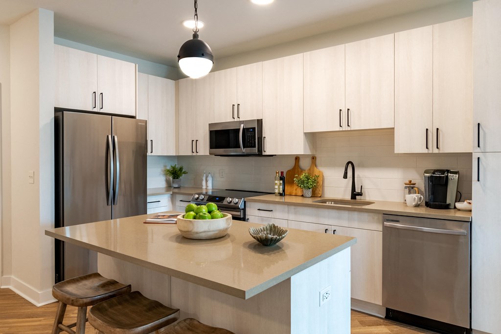 a kitchen with white cabinets and a large island with a bowl of fruit on it  at Century West Pryor, Missouri