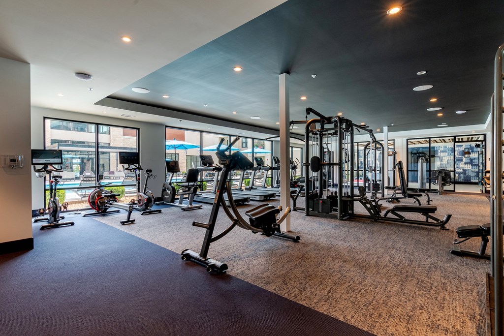 a gym with exercise equipment and large windows  at Century West Pryor, Lee's Summit, MO