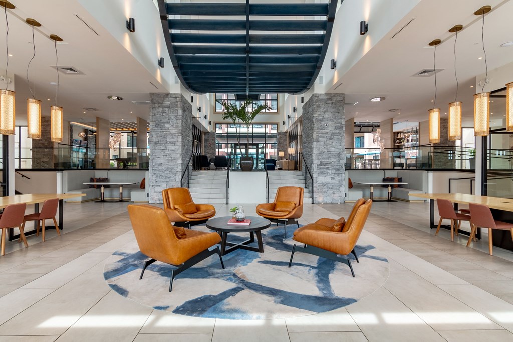 a large lobby with orange chairs and tables  at Century West Pryor, Missouri