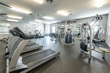 a gym with cardio equipment and weights on the floor