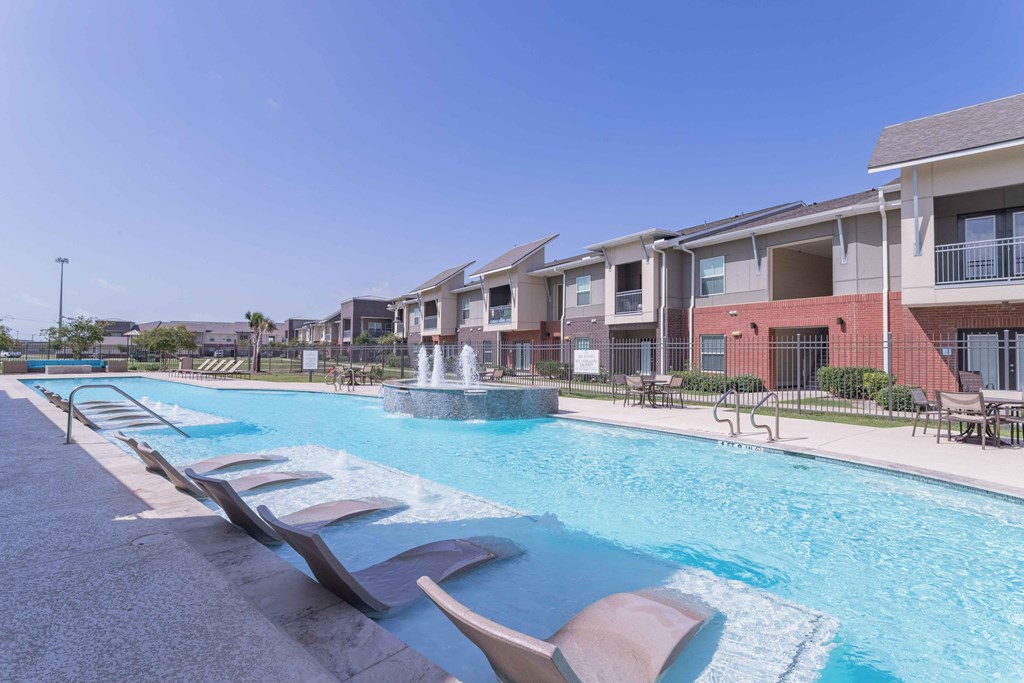 our apartments offer a swimming pool with chairs and a fountain at Century Palm Bluff, Portland, TX, 78374