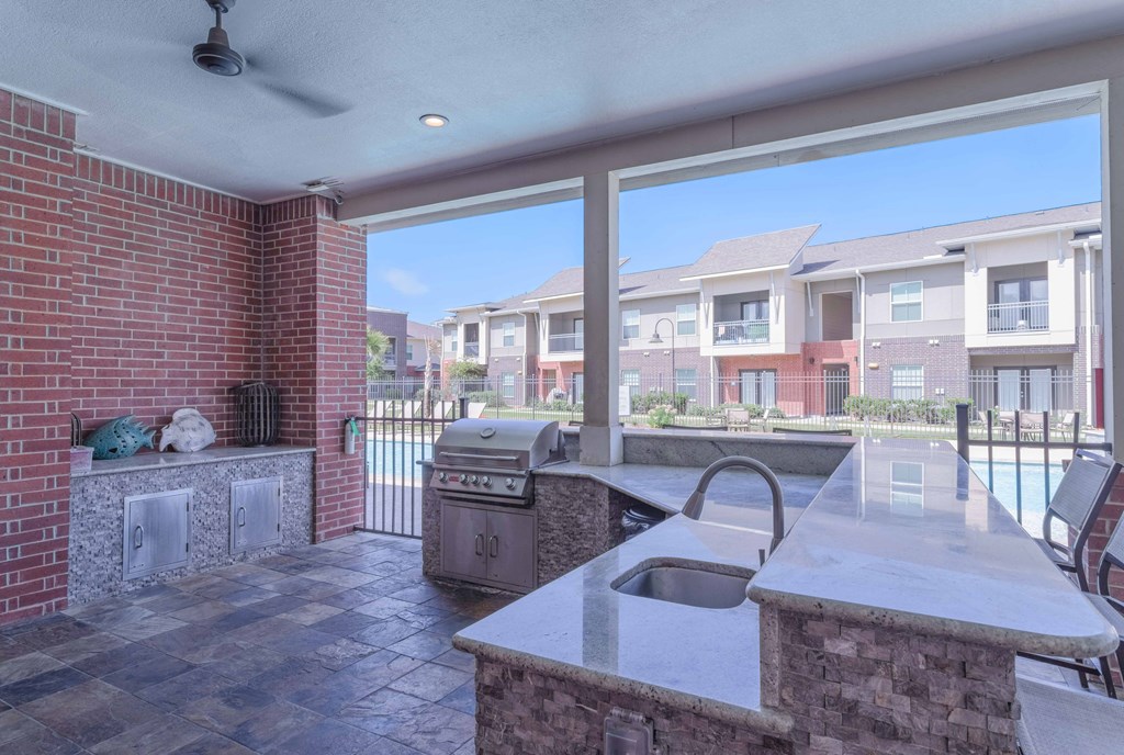 an outdoor kitchen with a grill and a large window at Century Palm Bluff, Portland, Texas