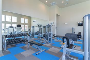 a gym with cardio equipment and weights in a building with windows at Century Palm Bluff, Portland, TX