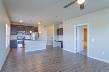 an empty living room with a kitchen and a ceiling fan at Century Palm Bluff, Portland, Texas