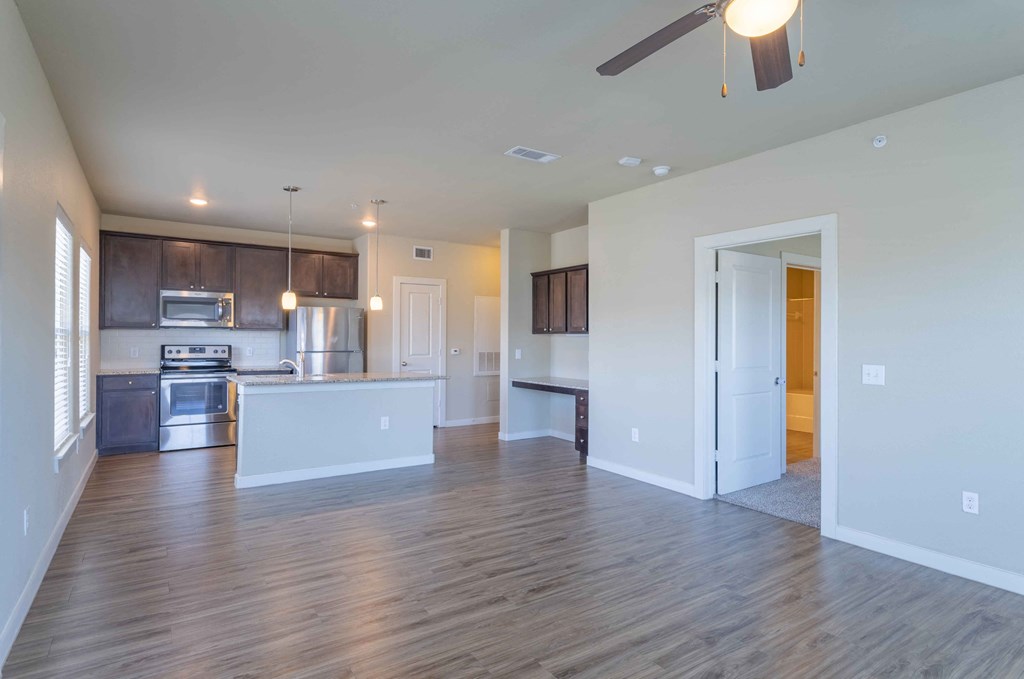 an empty living room with a kitchen and a ceiling fan at Century Palm Bluff, Portland, Texas