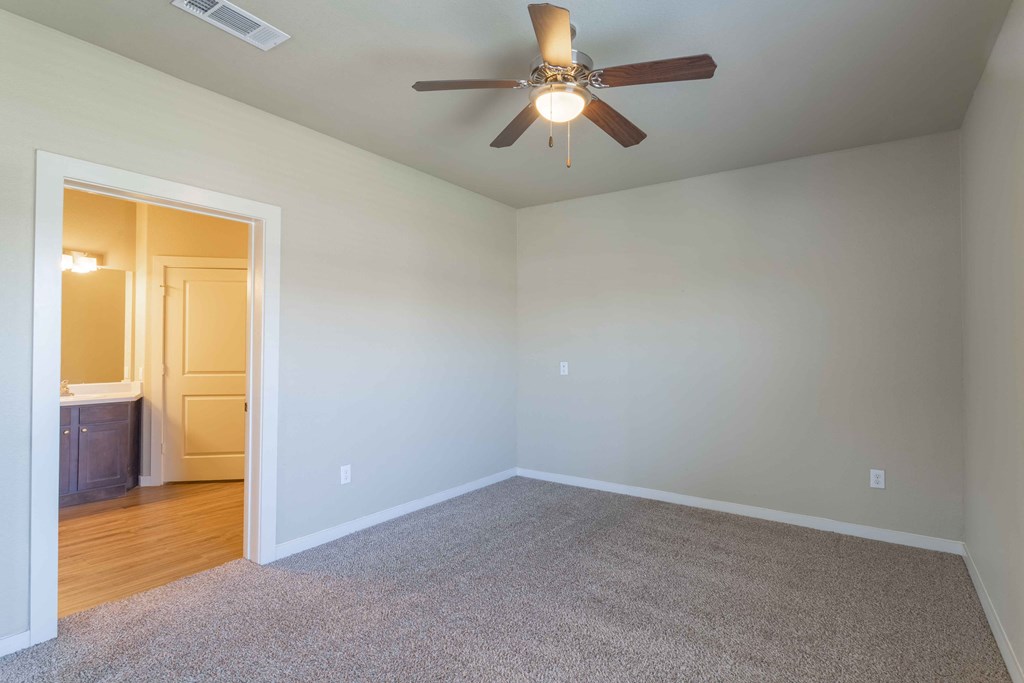 a bedroom with a ceiling fan and a door to a bathroom at Century Palm Bluff, Portland, 78374