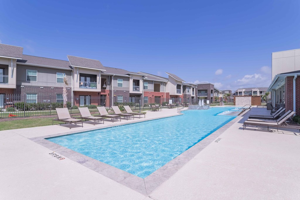 our apartments offer a swimming pool with lounge chairs at Century Palm Bluff, Portland, TX