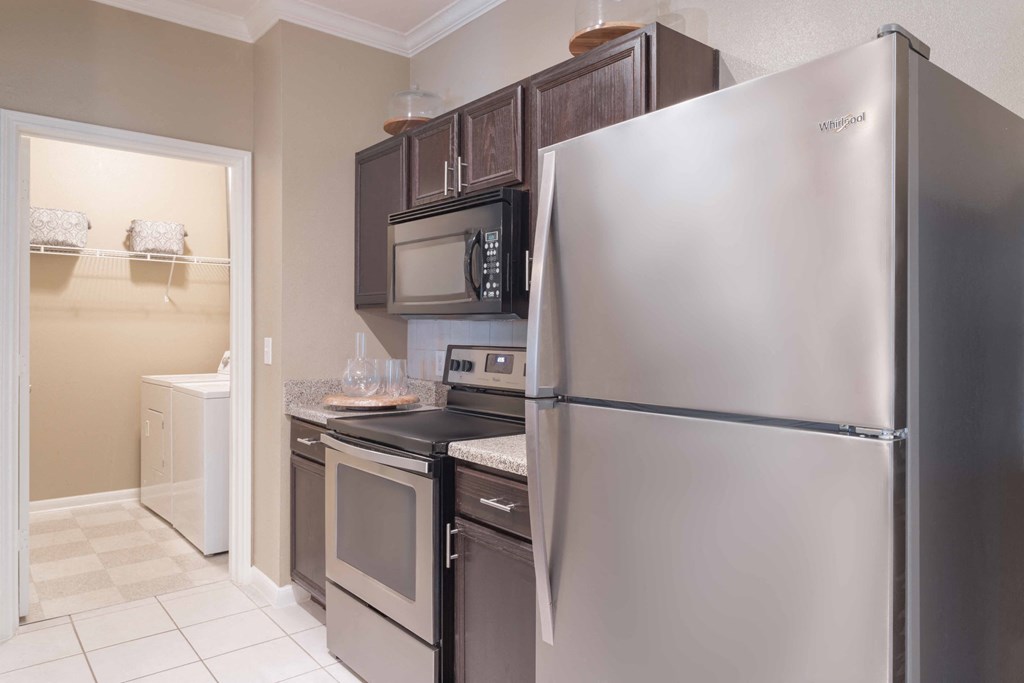 a kitchen with stainless steel appliances and black cabinets at Century South Shore, League City, Texas