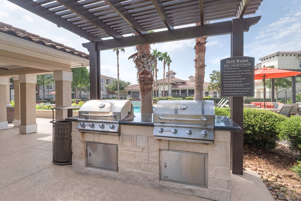 an outdoor grill area with two bbq grills under a pergola at Century South Shore, League City, TX