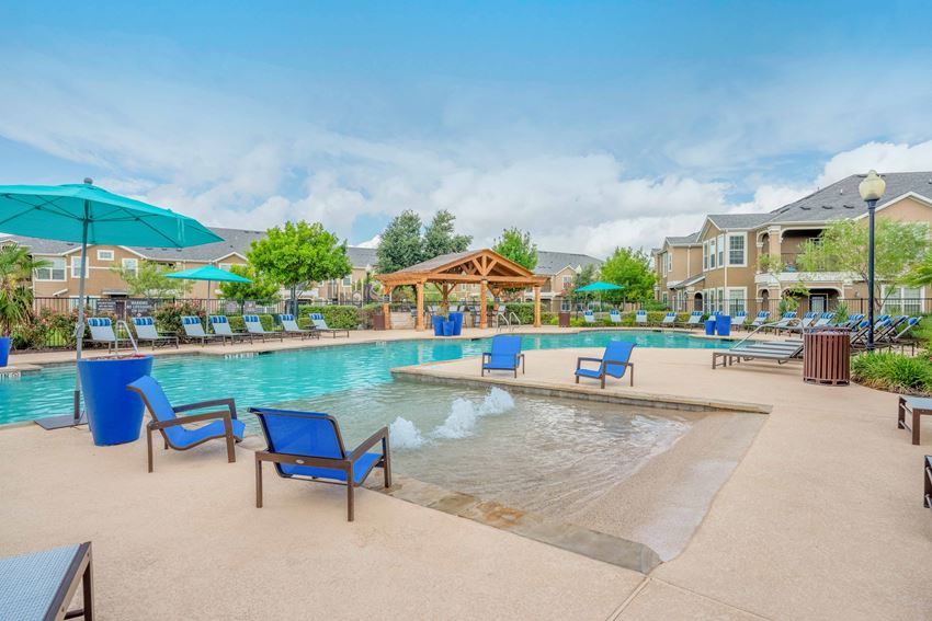 a swimming pool with chairs and umbrellas and a building in the background