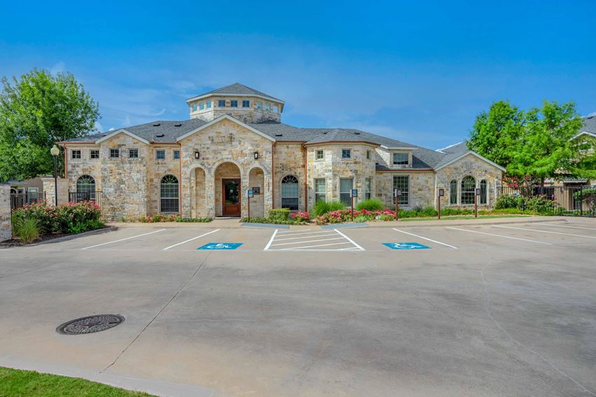 a large parking lot in front of a stone building with a driveway