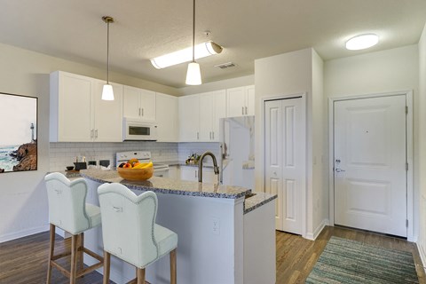 a kitchen with white cabinets and a counter top with two chairs