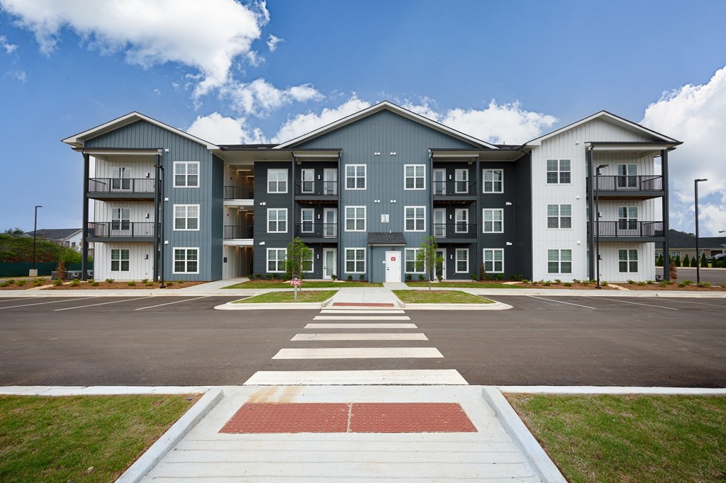 A large apartment complex with a red and white crosswalk in front.