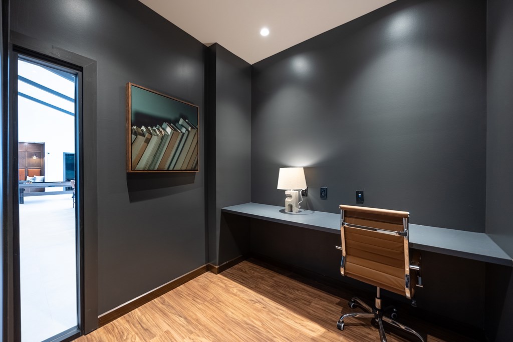 A room with a wooden chair and a desk with a lamp on it.